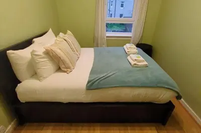 a bedroom with a bed with pillows and a window at Cozy two bed flat near Glasgow Airport & Paisley - Pass the Keys in Paisley