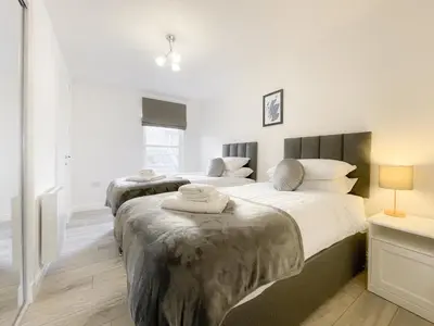 two beds in a bedroom with white walls at Pier View Apartment in Oban