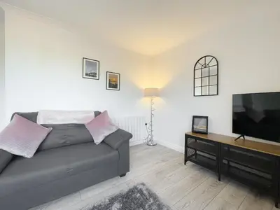 a living room with a couch and a flat screen tv at Pier View Apartment in Oban