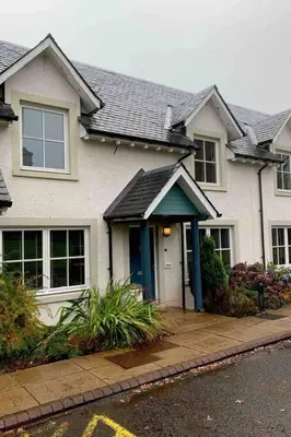 a white house with a blue door on a street at Ryder Cup Lodge Duchally - Free access to Leisure Club Swimming Pool Hot Tub Steam Room - Starlink Satellite Internet - Sky Glass Now DOG FRIENDLY for 2025 in Auchterarder