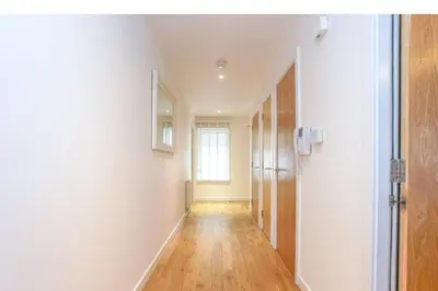 a hallway with white walls and a wooden floor at Oswald Apartment - Glasgow City Centre in Glasgow
