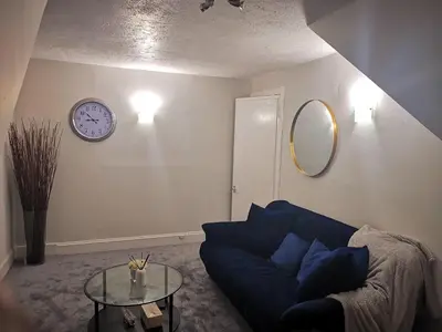 a living room with a blue couch and a clock on the wall at Welcome to St Helena Dunoon, a traditional villa in Dunoon