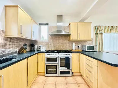 a kitchen with wooden cabinets and a stove top oven at Millerston House in Glasgow