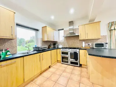 a kitchen with wooden cabinets and a stove top oven at Millerston House in Glasgow