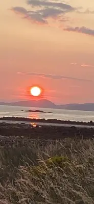 a sunset on the beach with the sun setting over the ocean at Glenashdale 28 A 1/R Boyd Street Largs KA308LE in Largs