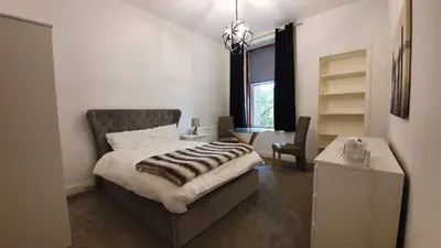 a bedroom with a bed and a desk and a window at Bemersyde Guest House in Mansewood
