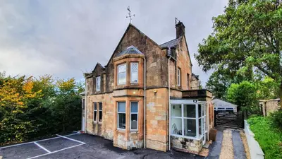 an old brick house with windows and trees at Bemersyde Guest House in Mansewood