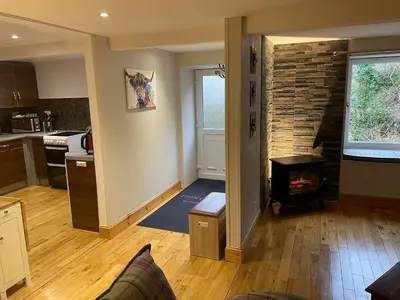 a living room with a fireplace and a kitchen at The Mews with Private Parking in Oban