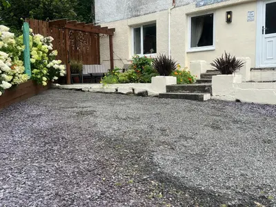 a house with a gravel driveway with flowers in front of it at The Mews with Private Parking in Oban