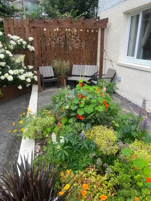 a garden with a bench and a bunch of flowers at The Mews with Private Parking in Oban