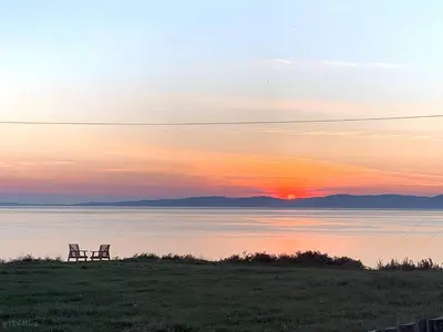 a bench sitting on the shore of a lake at sunset at North Muasdale Farm in Muasdale