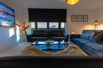 a living room with a blue couch and a table at The Skyline Suite - *Private Balcony* *Views* in Glasgow