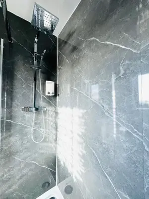 a bathroom with a shower with a gray marble wall at Tillicoultry Jupiter Apartment - Scotland Holiday Let in Tillicoultry