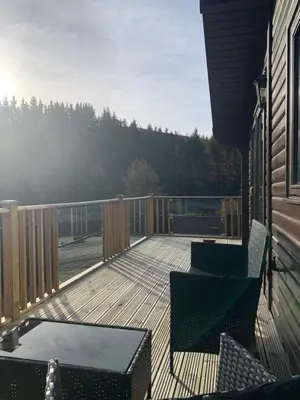 a deck with chairs and tables on a house at Corrie Lodge, Glendevon in Glendevon