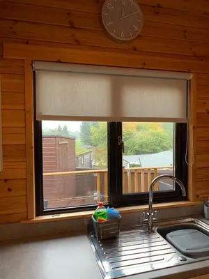 a kitchen window with a sink and a clock on the wall at Corrie Lodge, Glendevon in Glendevon