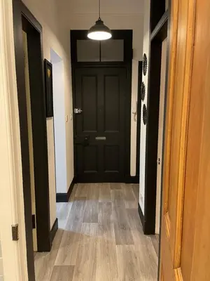 a hallway with a black door and wooden floors at Heart of George street / Oban / Argyll in Oban