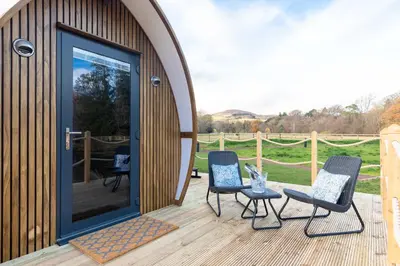 a wooden deck with chairs and a gazebo at The Secret Hideaway in Penicuik