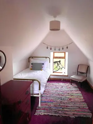 a attic bedroom with a bed and a window at Wee Silverburn in Whiting Bay