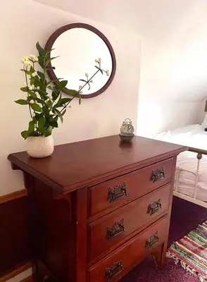 a bedroom with a dresser with a mirror on it at Wee Silverburn in Whiting Bay