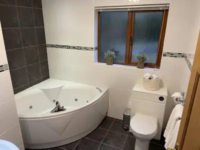 a white bathroom with a tub and a toilet at Foxglove Cottages in Drymen