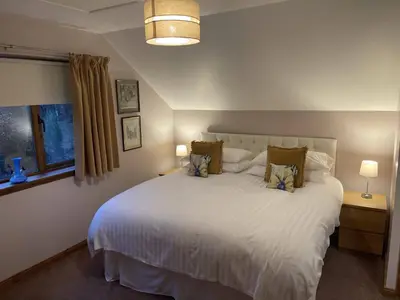 a bedroom with a large white bed with pillows at Foxglove Cottages in Drymen