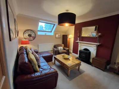 a living room with a leather couch and a table at Andreu Cottage in Callander