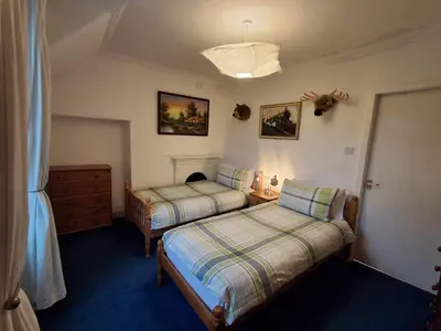 a bedroom with two beds and a dresser and a lamp at Andreu Cottage in Callander