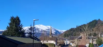 a town with a snow covered mountain in the background at Andreu Cottage in Callander