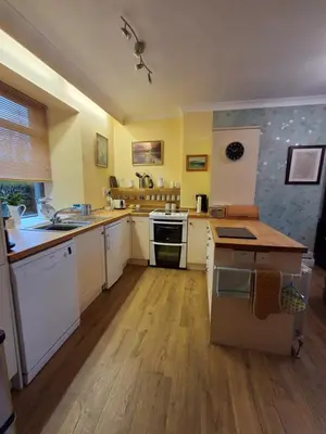 a large kitchen with white appliances and wooden floors at Andreu Cottage in Callander