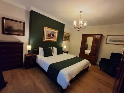 a bedroom with a bed with a green accent wall at Andreu Cottage in Callander