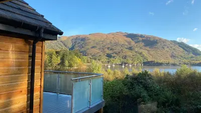 a cabin with a view of a lake and a mountain at The Heronry Hideaway with luxury hot tub in Ballachulish