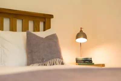 a bed with a pillow and a lamp on a table at The Heronry Hideaway with luxury hot tub in Ballachulish