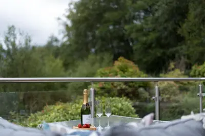 a bottle of wine sitting on a table with glasses at The Heronry Hideaway with luxury hot tub in Ballachulish
