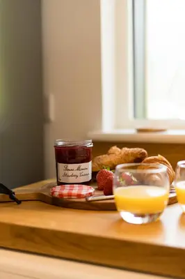 a tray with a plate of food and a jar of jam and orange juice at The Heronry Hideaway with luxury hot tub in Ballachulish