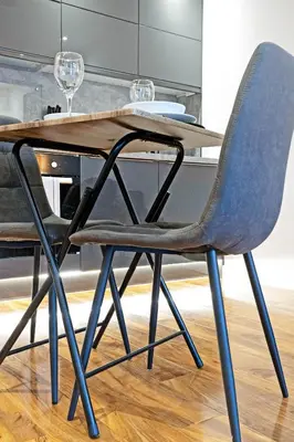 a dining table with a blue chair and a table with wine glasses at Pitcorthie House in Dunfermline