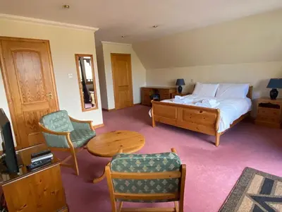 a bedroom with a bed and a table and chairs at Ghillies Lodge Crianlarich in Crianlarich