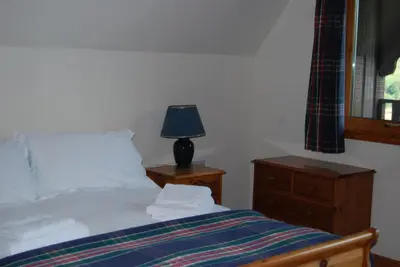 a bedroom with a bed with a lamp and a dresser at Ghillies Lodge Crianlarich in Crianlarich