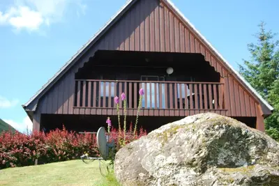 a building with a large rock in front of it at Ghillies Lodge Crianlarich in Crianlarich