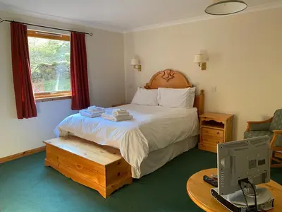 a bedroom with a bed and a desk with a computer at Ghillies Lodge Crianlarich in Crianlarich