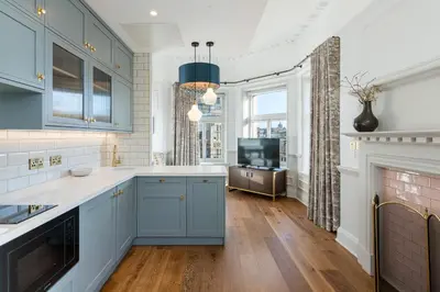 a kitchen with blue cabinets and a fireplace at RÌGH Residences - George Street in Edinburgh