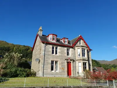 an old stone house with a red door at Tayview in Killin