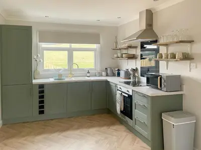 a kitchen with green cabinets and a sink at Mossdale Cottage in Dalmellington