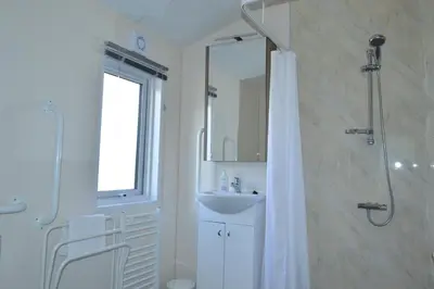 a white bathroom with a shower and a sink at Sunnybrae, Isle of Luing in Cullipool