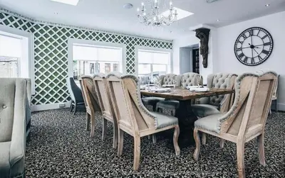 a dining room with a table and chairs and a clock at Mango the Hotel in Haggs