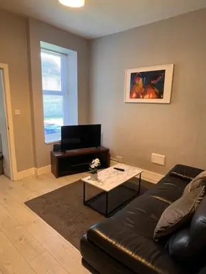 a living room with a leather couch and a table at Kelpies Serviced Apartments- Robertson in Falkirk