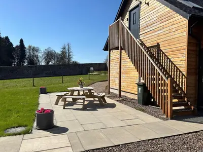 a patio with a picnic table next to a building at Cosy Country Modern Studio with Patio Space. in Crieff