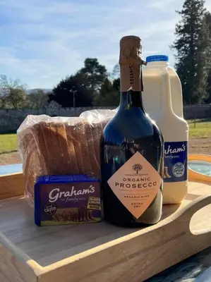 a bottle of wine and a gallon of milk on a table at Cosy Country Modern Studio with Patio Space. in Crieff