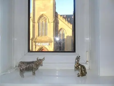 a couple of figurines sitting on a shelf in a window at Snug - Abhainn Apartment in Helensburgh