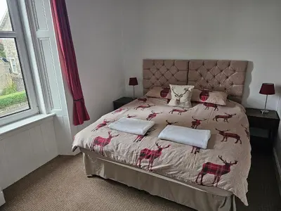 a bedroom with a bed with red deer pillows on it at Snug - Abhainn Apartment in Helensburgh