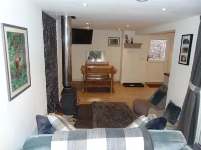 a living room with a couch and a piano at Dreamwood Cottage, Loch Lomond, Luxury Apartment. in Glasgow